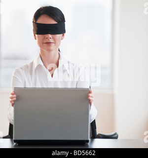 Businesswoman using laptop while blindfolded Stock Photo