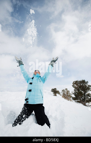 A woman throwing snow up in air Stock Photo