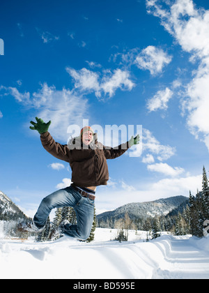 A man outdoors in snowy surroundings jumping Stock Photo