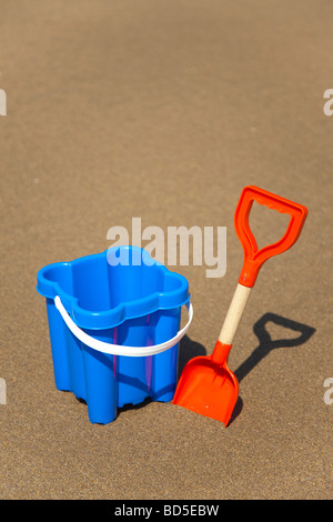 Blue sand castle bucket  with red spade on sandy beach, Whitsand Bay, Cornwall Stock Photo
