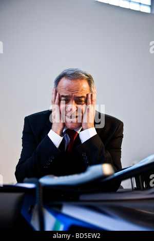 Desperate manager in front of a mountain of folders Stock Photo
