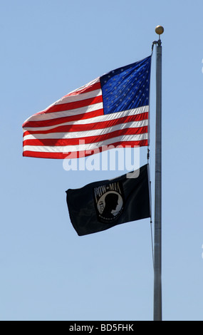 A POW-MIA flag flies below the American flag on a flag pole Stock Photo