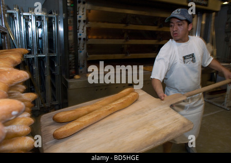 Workers at Amy s Bread in Chelsea Market in New York bake loaves of bread in the bakery s commercial ovens Stock Photo