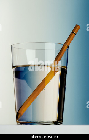 Yellow pencil in glass of water showing refraction Stock Photo