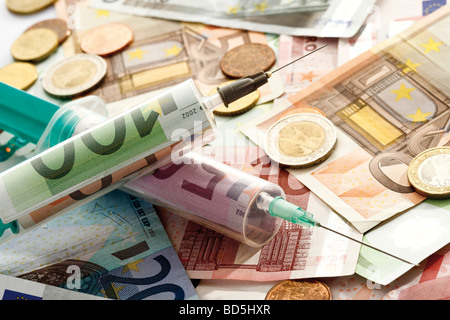 Banknotes, coins, syringes, symbolic picture for injecting money Stock Photo