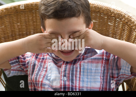 Little boy hands over eyes Stock Photo