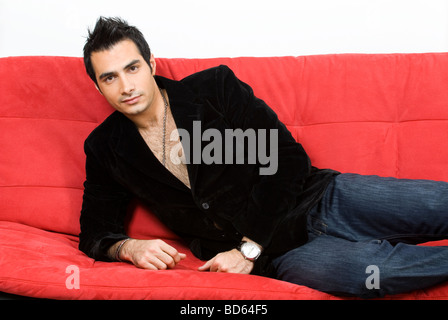 Man lying on red couch Stock Photo