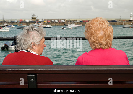 st ives holiday couples sitting on a bench and looking out to sea and over the harbour Stock Photo