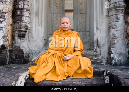 Young Buddhist monk Ronrom sits in a doorway at East Mebon, one of the temples of Angkor in Siem Riep province, Cambodia. Stock Photo