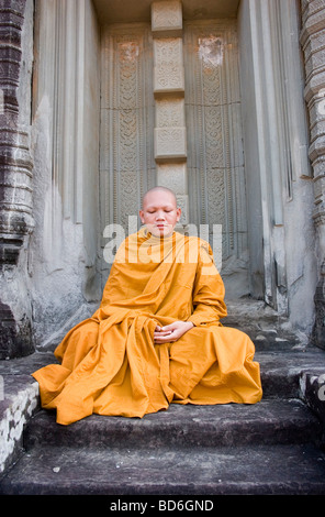 Young Buddhist monk Ronrom sits in a doorway at East Mebon, one of the temples of Angkor in Siem Riep province, Cambodia. Stock Photo