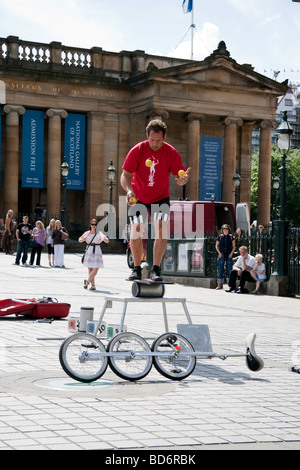 A street performer juggling and balancing during an act outside the gallery on Edinburgh's Mound during the Fringe Festival Stock Photo