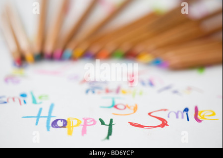 Coloured smile, happy, joy, fun words on paper with colouring pencils Stock Photo