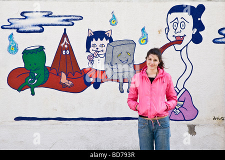 Caucasian girl posing in front of colourful graffiti on the streets of Tokyo Stock Photo
