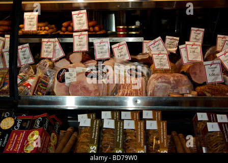 Delicatessen specialty cured meats in illuminated stainless steel display cooler case Stock Photo