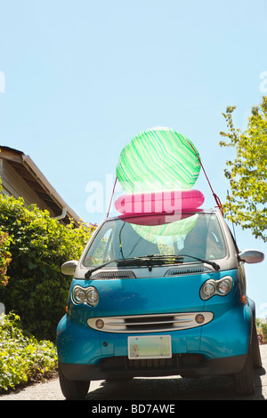 Woman with beach ball on smart car Stock Photo
