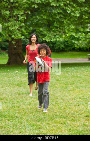 Boy with football running from mother Stock Photo