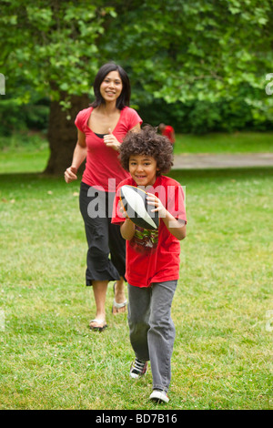 Boy with football running from mother Stock Photo