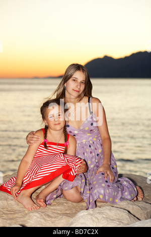 Two girls sitting by the sea Stock Photo