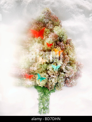 Dried hydrangeas in the shape of a tree shape decorated with origami butterfly ornaments on a bed of snow. Stock Photo