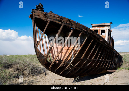 A rusty fishing boat at the cemetery of ships (Ships' Graveyard) in Moynaq, former fishing port town near Aral Sea, Uzbekistan. Stock Photo