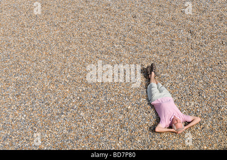 mature man laying on shingle beach Stock Photo