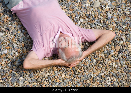 overview of mature man laying on shingle beach Stock Photo