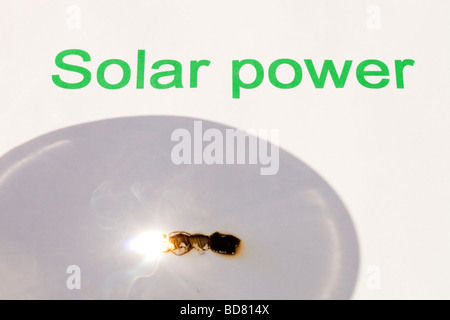 Solar power concentrating the suns power through a magnfying glass Stock Photo