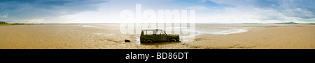 Panoramic view of a partially submerged wreck of a car on the beach at Bolton le Sands, Morecambe Bay. UK Stock Photo