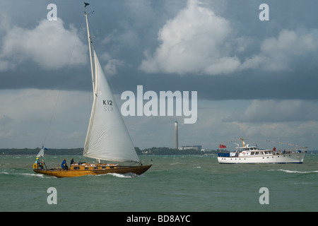 Wooden yacht passing a cabin cruiser on the Solent viewed from the Esplanade Cowes  Isle of Wight England Stock Photo