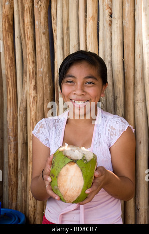 A happy young Mexican girl offers and ice cold coconut for sale to tourists visiting Chichen Itza. Stock Photo