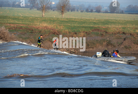 Surfers riding the Seven Bore at Stone bench in gloucestershire England being filmed by a TV crew Stock Photo