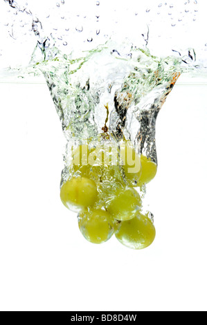 Green grapes splashing into water over a white background Stock Photo