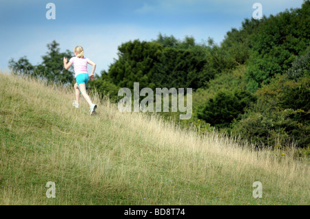 Royalty free photograph of healthy girl running up a hill in a British national park in the summer sunshine UK Stock Photo