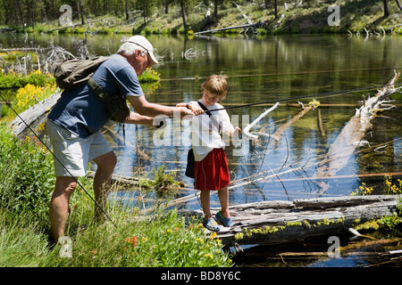Grandfather teaching young grandson fly fishing in the Cascades near Bend, Oregon