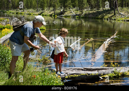 Grandfather teaching young grandson fly fishing in the headwaters of the Deschutes River near Bend, Oregon, USA