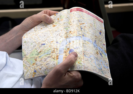 Close up of an A-Z type street map in a guide book of Central London held open in a young man's hands. Stock Photo