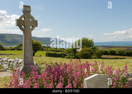 A Celtic cross in graveyard in The Burren, County Clare, Ireland with a view of Kinvara Bay. Stock Photo