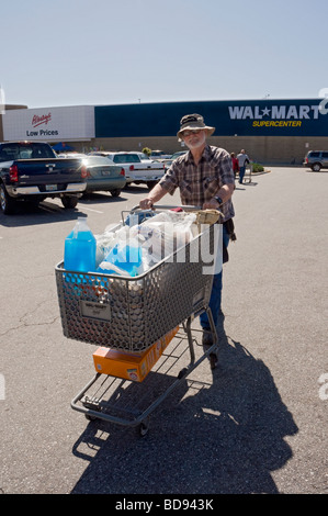 older man with shopping cart full of items in parking lot of Wal Mart store Stock Photo