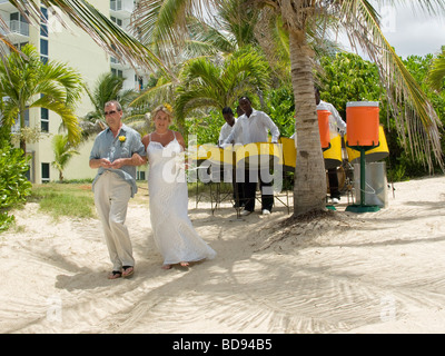 A bride and her father look nervous as they walk down to the beach for her tropical wedding Stock Photo