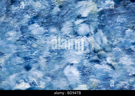 Abstract - Fast flowing blue water over stones close up Stock Photo
