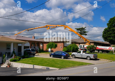 Concrete pumping truck reaching over a house to pour in back yard Toronto Stock Photo