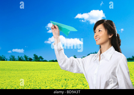Chinese girl playing paper airplane in the field Stock Photo