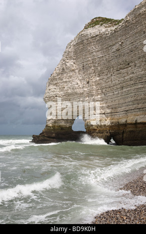 Waves breaking against the limestone cliffs at Etretat, Normandy. The cliffs include layers of flint and are rich with fossils, France, Europe Stock Photo