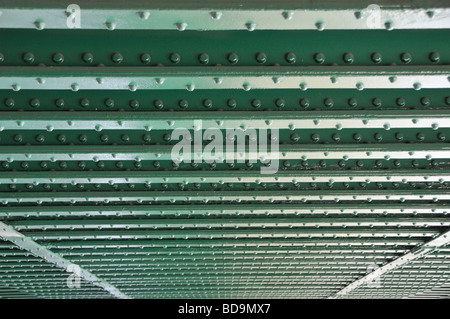 Lines of rivets in steel girders on underside of railway bridge over river close up Stock Photo