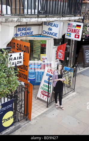 High angle of young woman standing outside a Bureau De Change amid promotional signs
