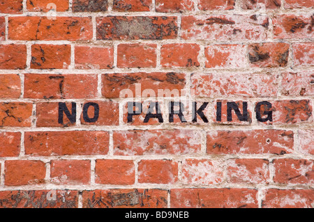 No Parking - signage painted in black on a red brick wall. UK Stock Photo