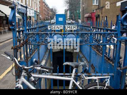 Padlocked bicycle chained against railings of closed Public Conveniences at Portobello Road Market in West London. Stock Photo