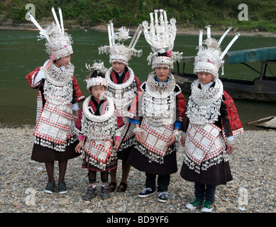 Five girls in formal dress at riverbank posing for photos at Miao Drum Festival Shidong Guizhou Province China Stock Photo