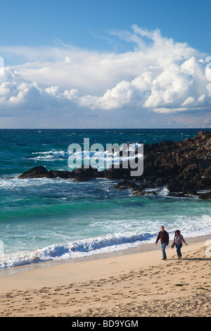 Middle-aged couple walk along Porthmeor beach in late evening summer sunshine St Ives Cornwall England UK United Kingdom GB Stock Photo