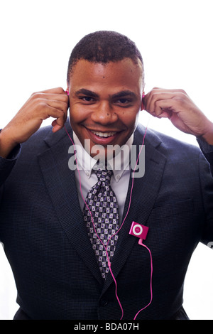 A young handsome man wearing a suit is listening to music on pink head phones. Stock Photo